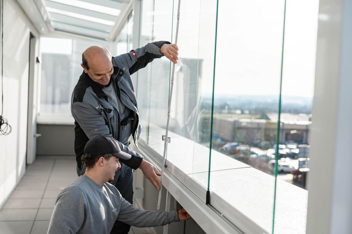 Zwei Monteure setzen eine große Glasscheibe ein.