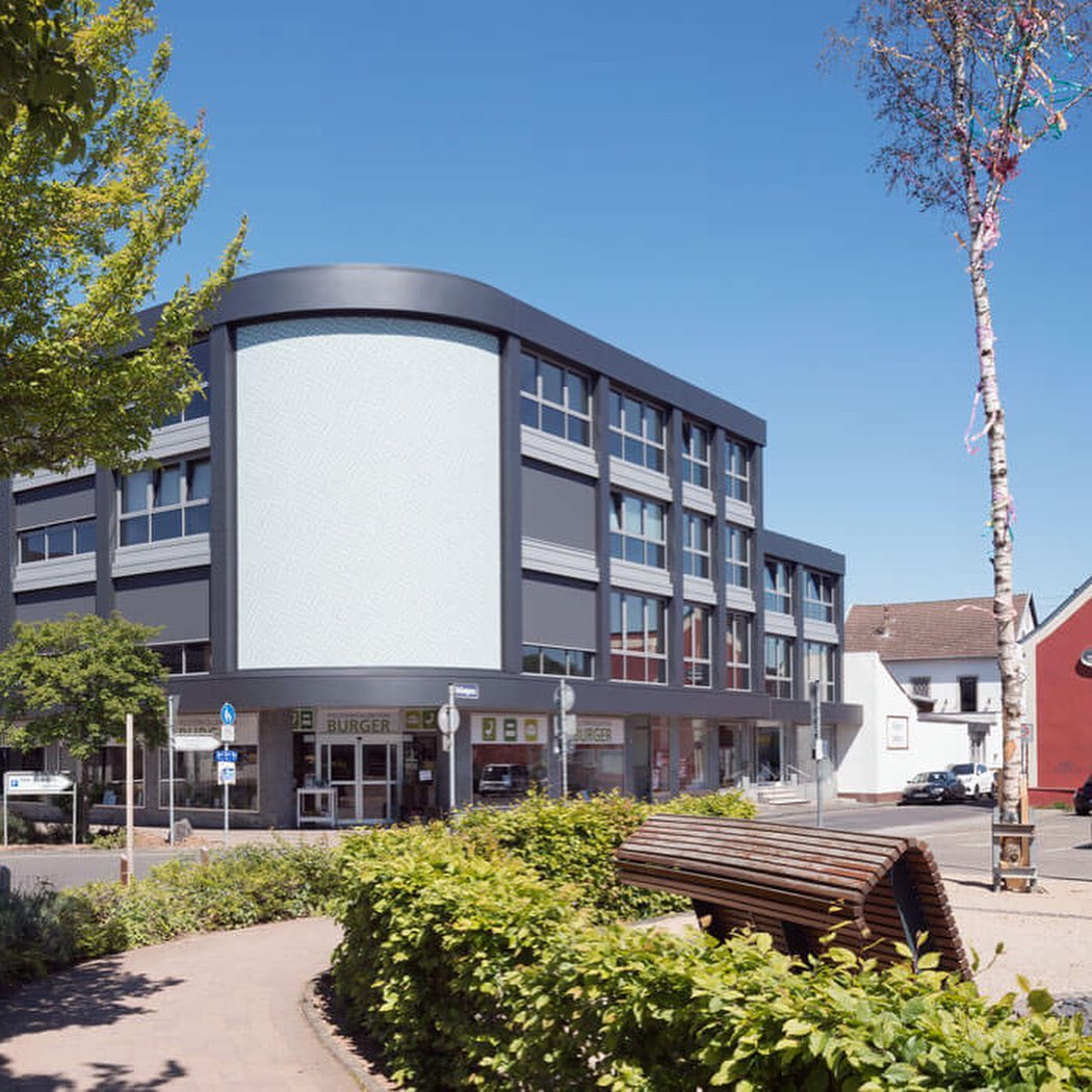 Das Geschäftshaus nach der Sanierung mit neuer Fassade, im Hintergrund der Kirchturm.