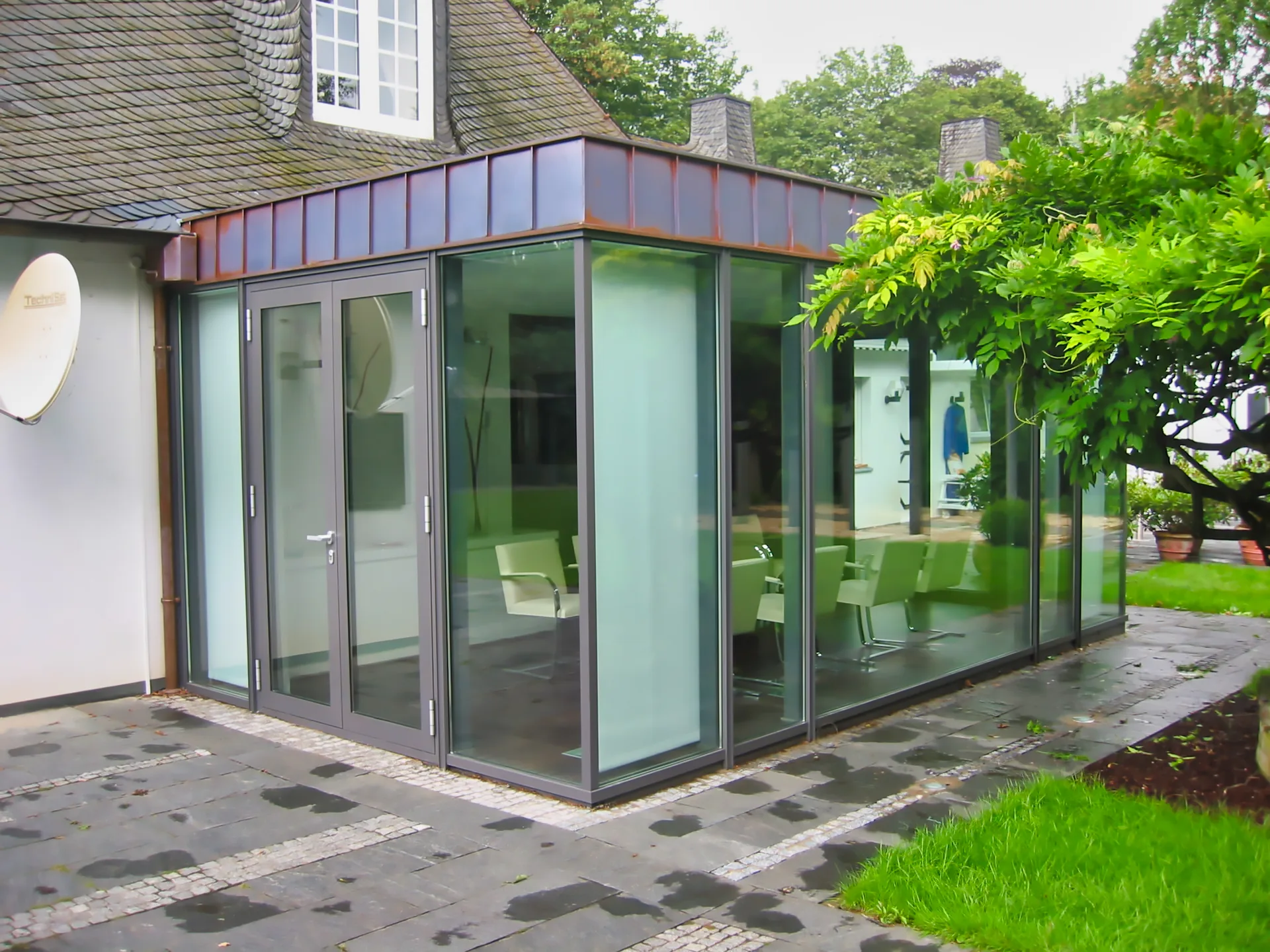 Glasanbau mit Flachdach an einem Wohnhaus.