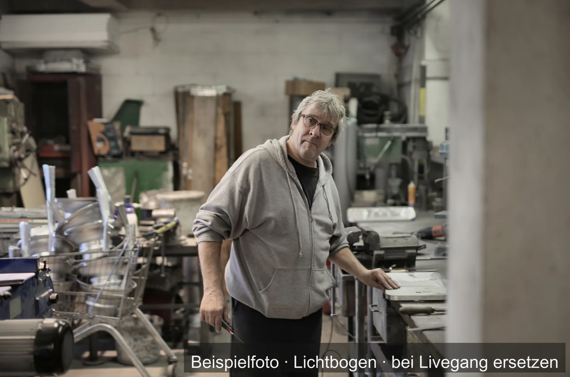 Mann in Arbeitskleidung in einer Metallwerkstatt.